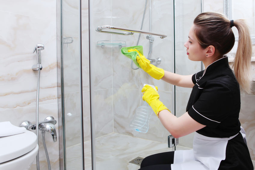 a woman cleaning shower doors from soap
