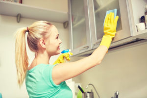 happy woman cleaning cabinet at home kitchen