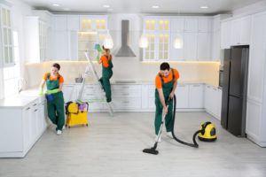 Team of professional janitors cleaning modern kitchen